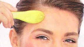 Place the Gua sha tool at the center of your forehead